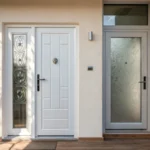 A modern entrance showcasing a white PVC door and a sleek aluminum door side by side.
