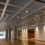 Modern interior with aluminum baffle ceiling and polished wood floor.
